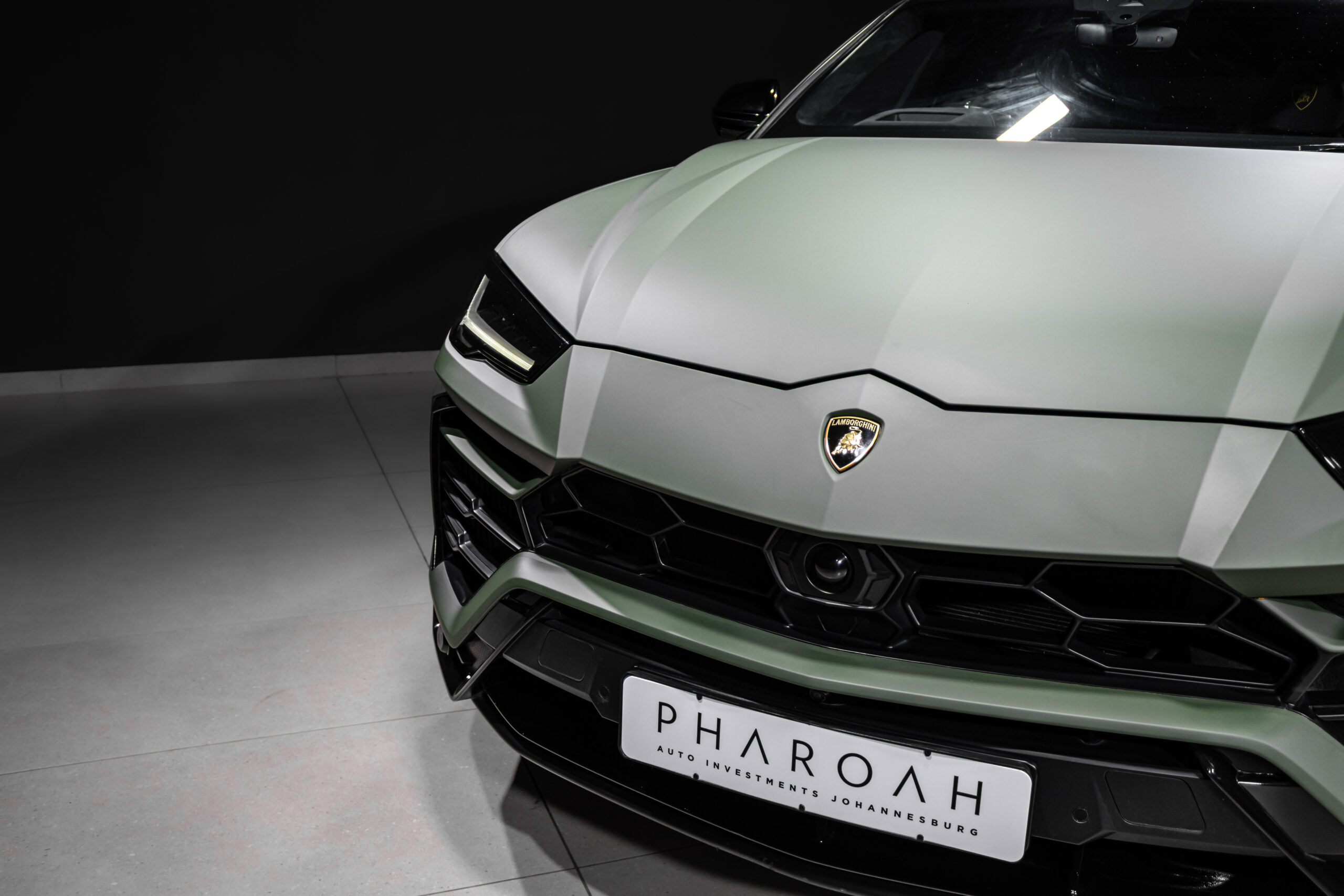 Front angled view of a silver Lamborghini with a sharp, geometric hood and prominent badge, partially showing the license pla