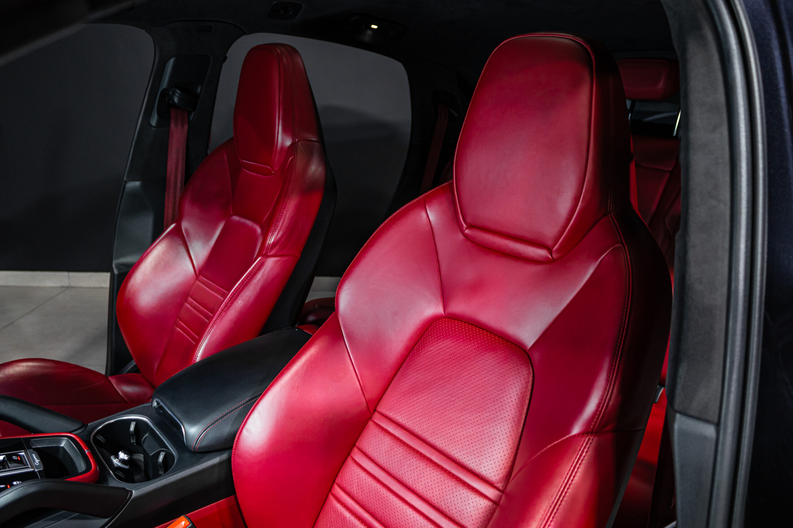 Red leather front car seats with a black center console visible in a luxury vehicle interior.