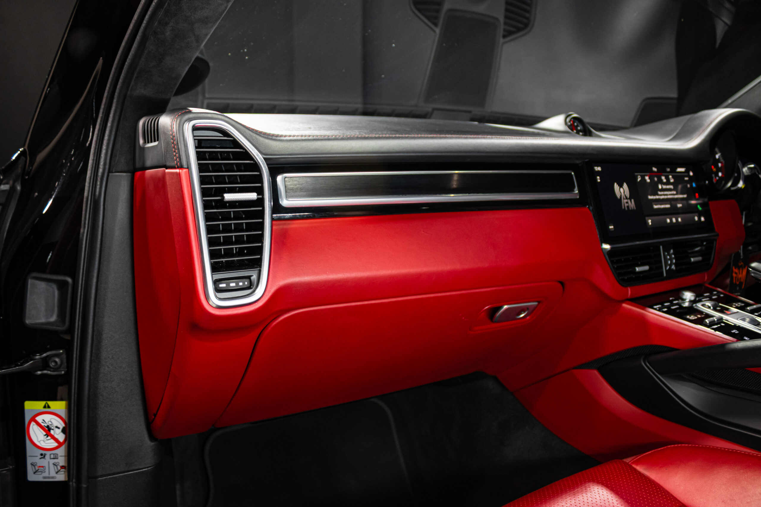 Red leather dashboard interior with black trim and a touchscreen center display in a luxury car