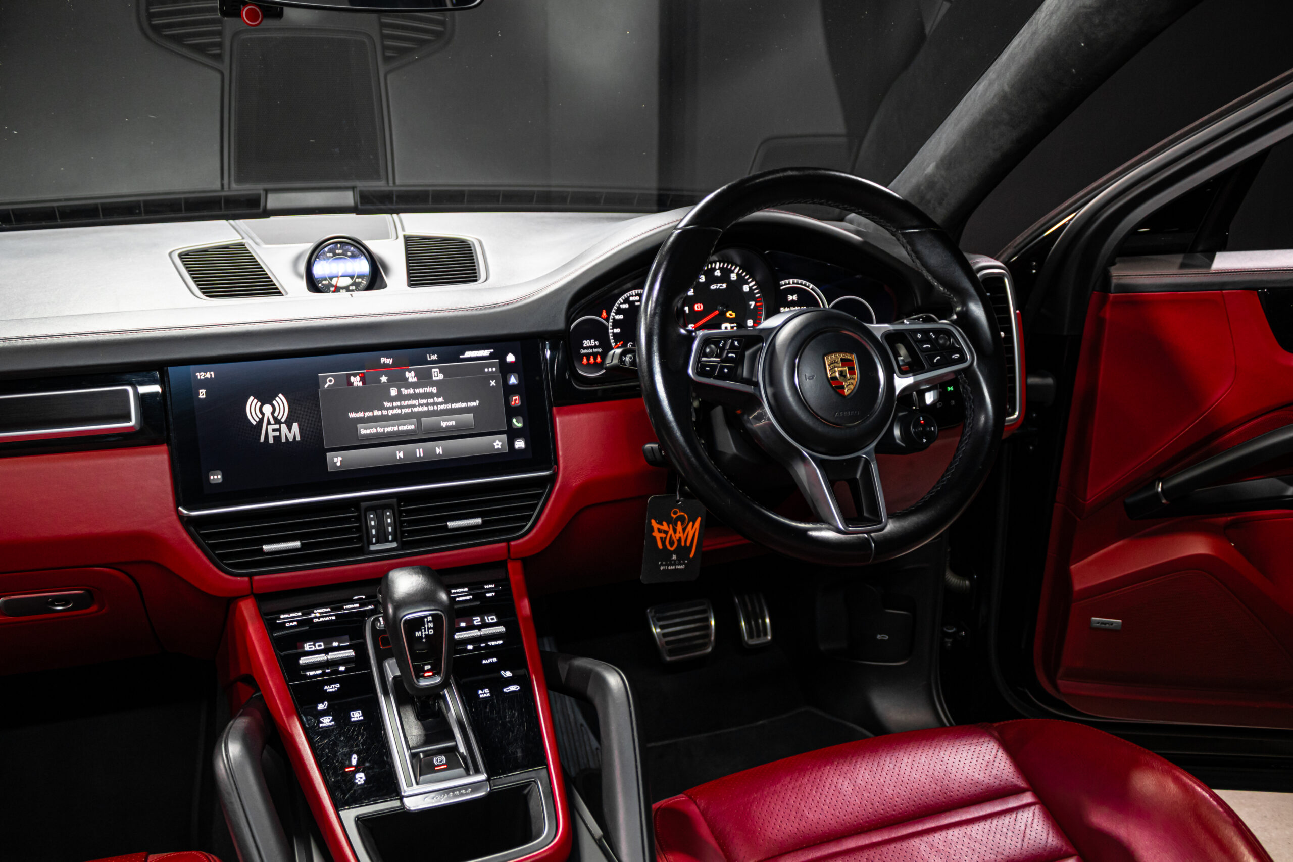 Porsche interior with red leather seats, black dashboard, and steering wheel featuring the Porsche emblem.