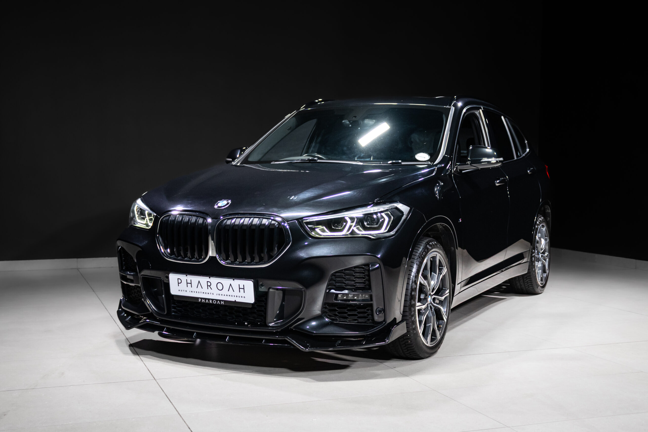 Black BMW SUV on a showroom floor, angled front view showcasing the grille and headlights