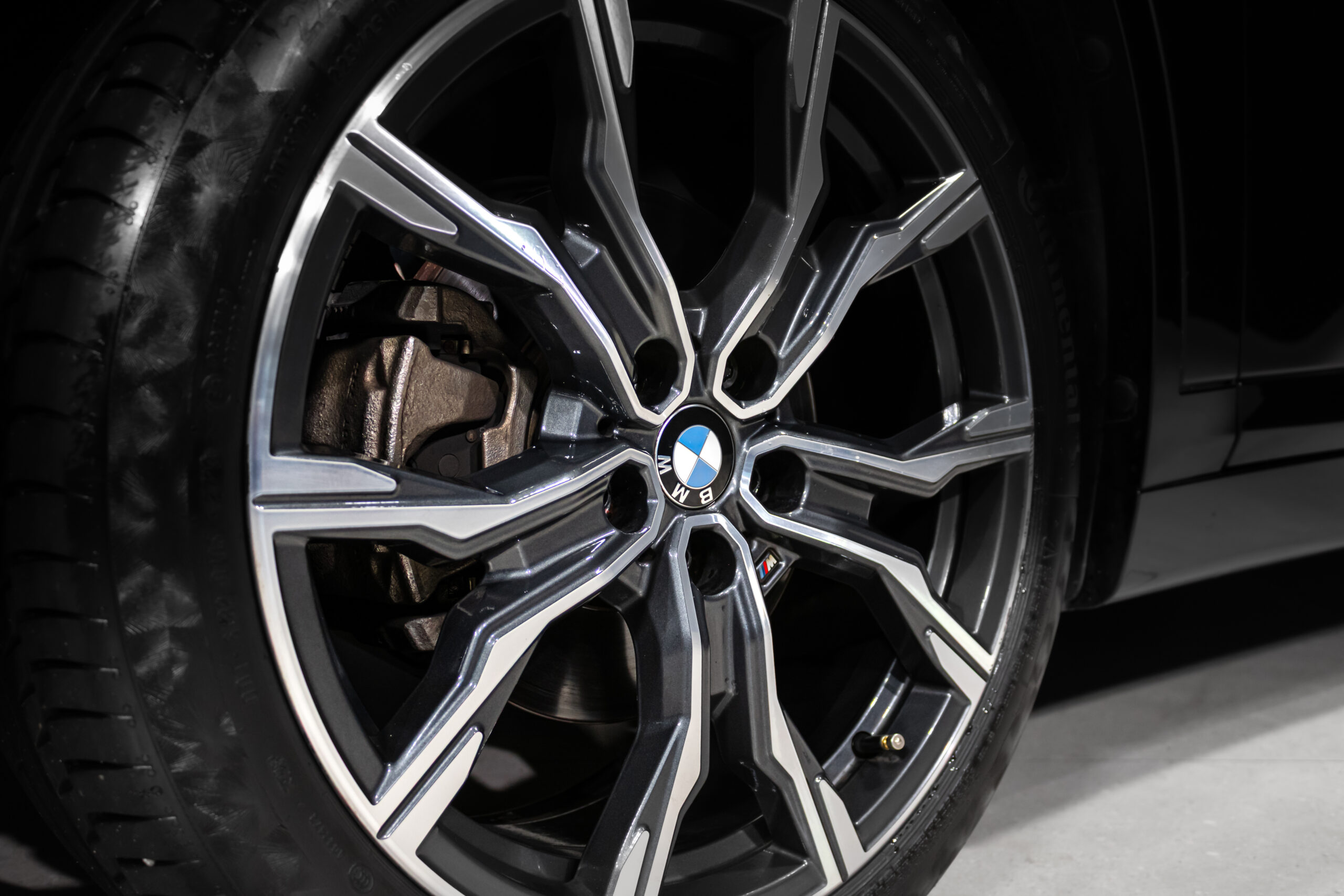 Close-up of a BMW alloy wheel with intricate spokes and the brake rotor visible behind.