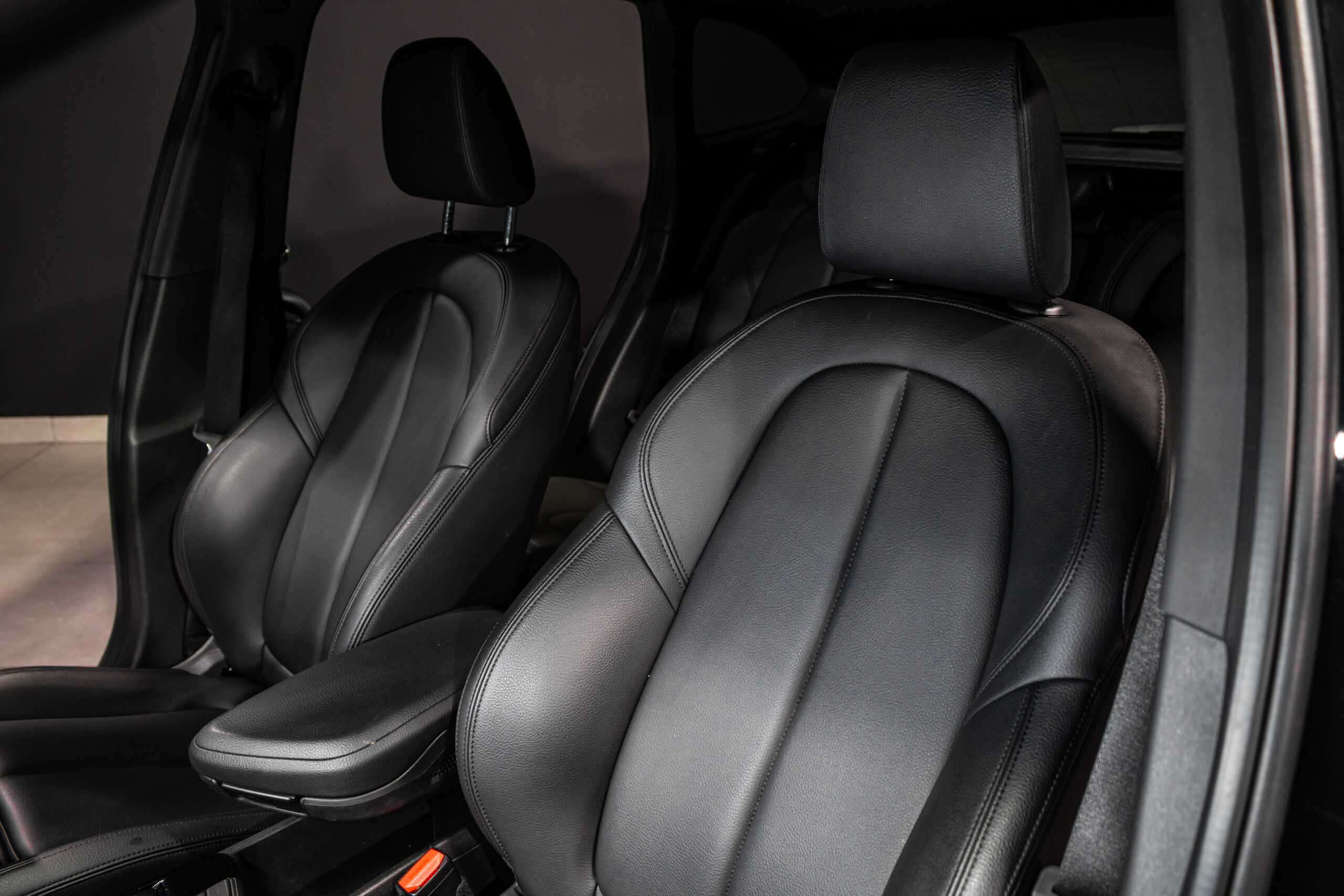 Black leather car seats with headrests in a vehicle interior, shown from the passenger side.