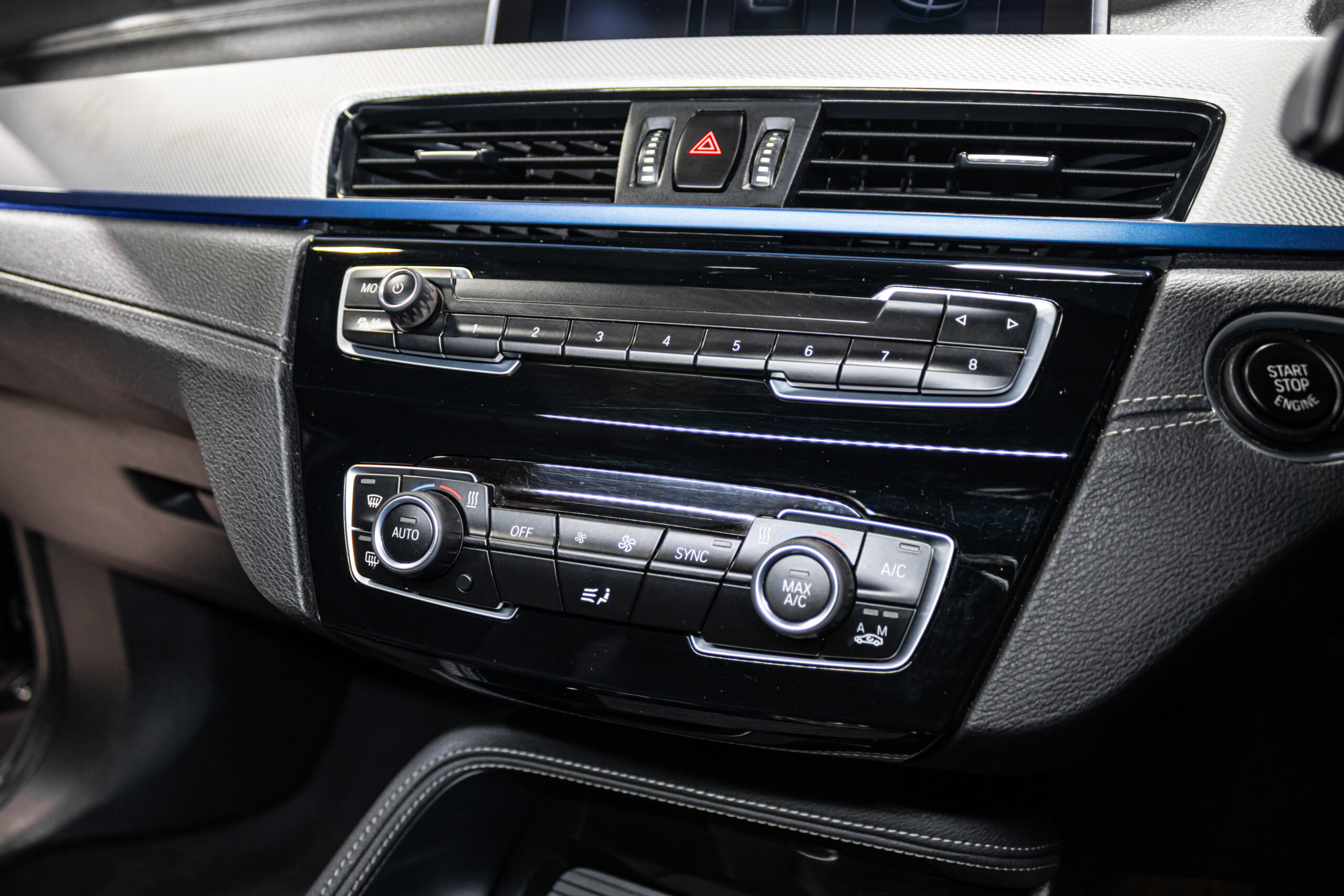 Center dash with climate controls, media buttons, and hazard switch in a premium car interior