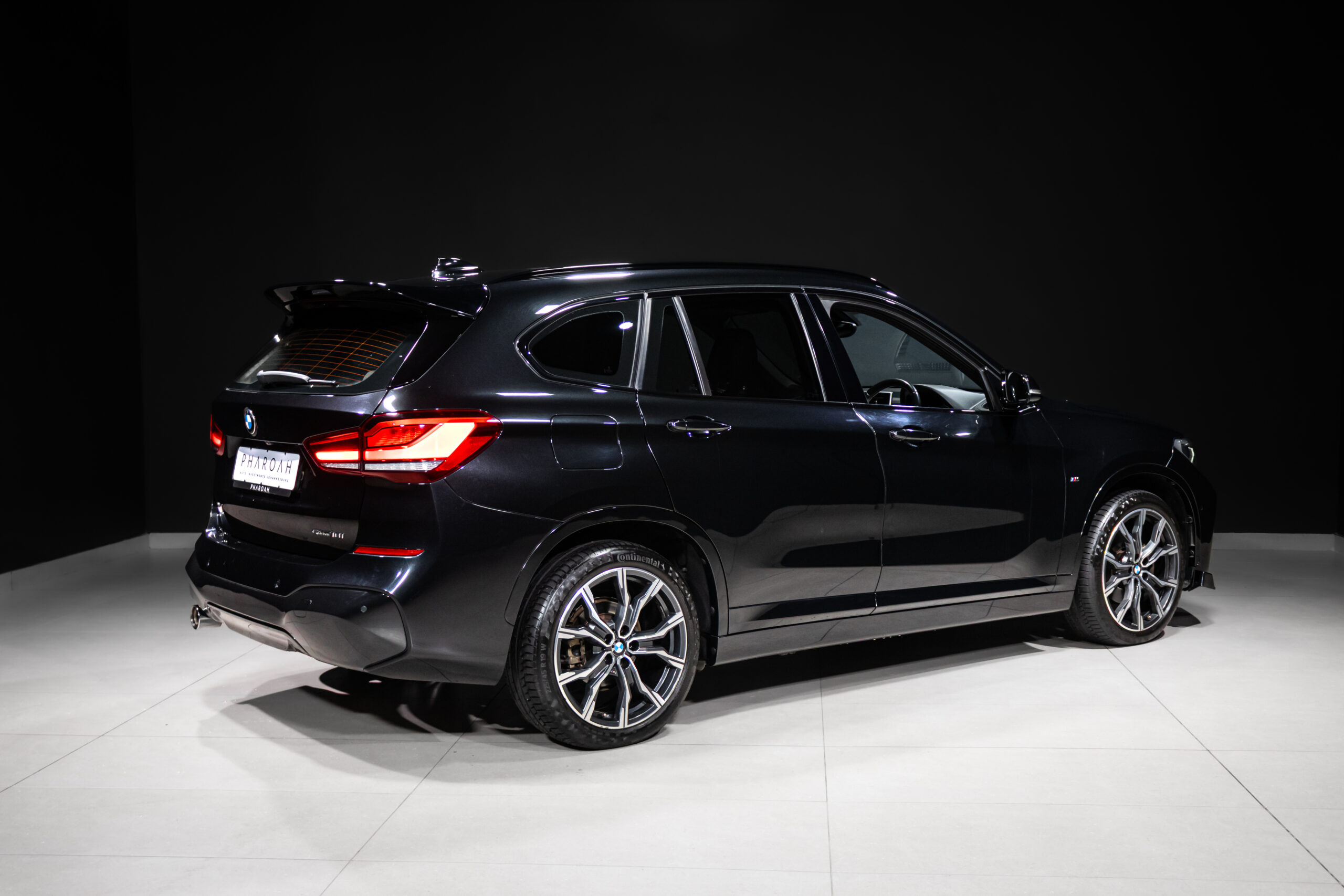 Black BMW SUV photographed in a studio, rear three-quarter view with glossy paint and alloy wheels.